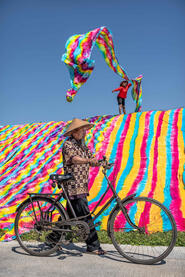 Colored Path Batik factory worker tossing fabric to dry in the sun © Roberto Pazzi