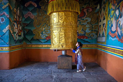 Spinning the Wheel Portrait of a child spinning a Buddhist prayer wheel inside a Dzong © Roberto Pazzi