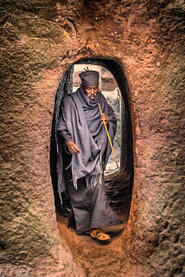 Tunnel of Faith Portrait of an Orthodox priest entering one of the eleven rock-hewn monolithic churches in Lalibela © Roberto Pazzi
