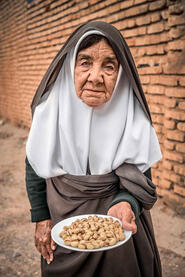 Humble Welcome Portrait of an elderly woman offering pistachios as a welcome gift © Roberto Pazzi